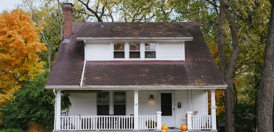 A house in the fall with visible roof damage.